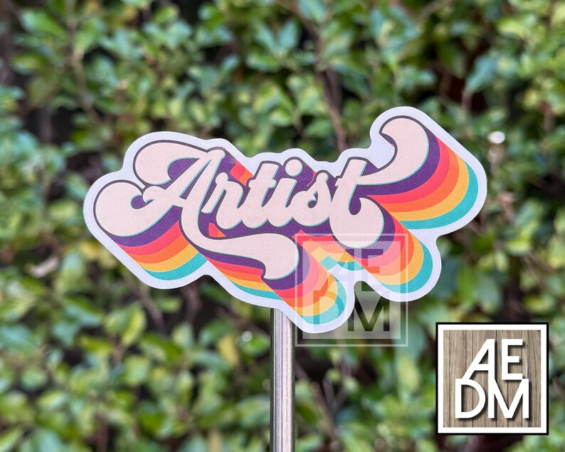 May include: A die-cut sticker featuring the word Artist in a bold, cursive font. The lettering is layered over a series of concentric, wavy rainbow-colored stripes in shades of purple, red, orange, yellow, and teal, creating a retro-inspired design.