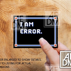 May include: A black sticker with the text "I AM ERROR" in white pixelated font, framed by a blue border. The sticker is held by a hand against a wooden background. The text "STICKER ENLARGED TO SHOW DETAILS. REFER TO LISTING FOR ACTUAL DIMENSIONS" is also visible.