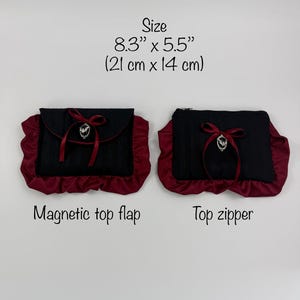 May include: Two black and burgundy clutch bags. One has a magnetic top flap, the other a top zipper. Each bag is 8.3" x 5.5" (21 cm x 14 cm) and features a burgundy ruffle trim, a bow, and a decorative emblem.