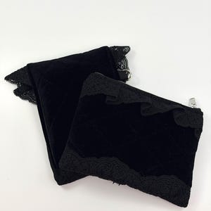 May include: Two black velvet zippered pouches with quilted stitching and decorative lace trim. The pouches are in a folded arrangement, showcasing the texture and design. The zippers are silver-toned.