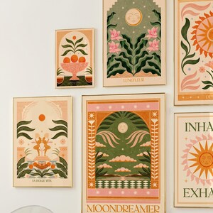 May include: A set of nine framed prints with a vintage aesthetic. The prints feature illustrations of moons, suns, flowers, and other nature-inspired elements. The prints are in a variety of colours, including pink, green, yellow, and orange. The prints are all framed in gold.