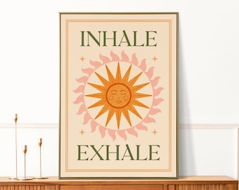 May include: A beige poster with a green border and the words "INHALE" and "EXHALE" in green text. A stylized orange sun with a closed-eye face is in the center of the poster with pink flames around it.
