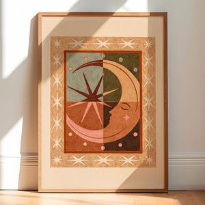 May include: Framed art print with a celestial theme. The artwork depicts a crescent moon with a face, a starburst, and stars in brown, green, and pink. The print is enclosed in a wooden frame.