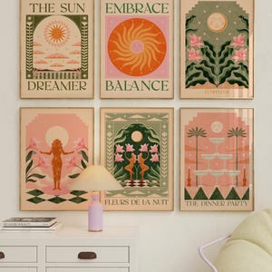 May include: Set of six illustrated prints with a bohemian aesthetic. Each print features a different design with a moon, sun, or flowers. The prints are framed in gold and have a light pink, orange, and green colour scheme. The text on the prints includes "The Sun Dreamer", "Embrace Balance", "Luneffur", "Fleurs de la Nuit", and "The Dinner Party".