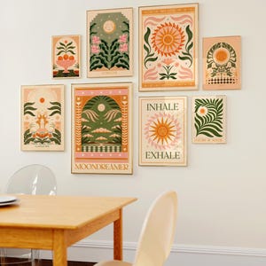 May include: A collection of eight framed prints with a nature theme. The prints feature illustrations of flowers, suns, moons, and other natural elements. The prints are in a variety of colours, including pink, green, yellow, and orange. The prints are arranged in a grid pattern on a white wall.