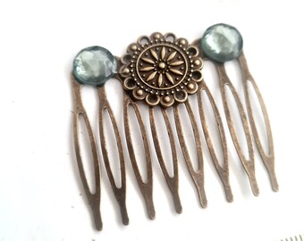 May include: A bronze hair comb with a decorative floral design and three light blue rhinestones.
