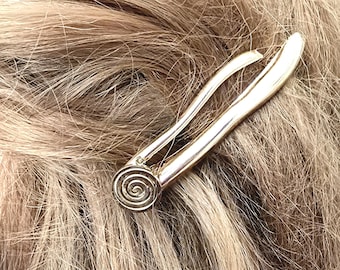 May include: A silver-toned hair clip with a spiral design at the base. The clip is inserted into light brown hair, showcasing its elegant and simple design. This accessory is perfect for adding a touch of sophistication to any hairstyle.