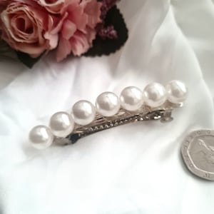 May include: A silver hair clip with a row of white pearl beads.