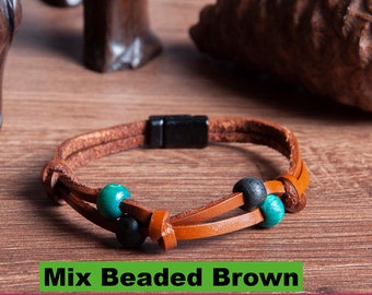 May include: Four leather bracelets with different colored beads. The bracelets are brown, black, and green. The bracelets are displayed on a wooden surface. The text "Mix Beaded Brown", "Brown Beaded Black", "Green Beaded Black", "DANA LEATHER DESIGN", "ARTS A CRAFTS", and "with in Gift Box" are visible in the image.