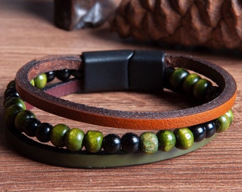 May include: A brown leather bracelet with a magnetic clasp and green and black wooden beads.