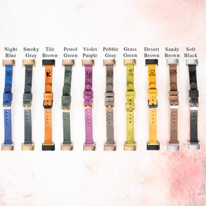 May include: Ten different coloured leather watch straps with various engraved designs. The straps are arranged in a row from left to right. The colours are: night blue, smoky grey, tile brown, petrol green, violet purple, pebble grey, grass green, desert brown, sandy brown, and soft black.