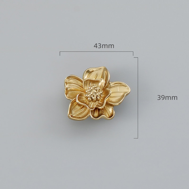 May include: Gold-toned metal flower-shaped drawer pull with a detailed design. The pull measures 43mm wide and 39mm high.