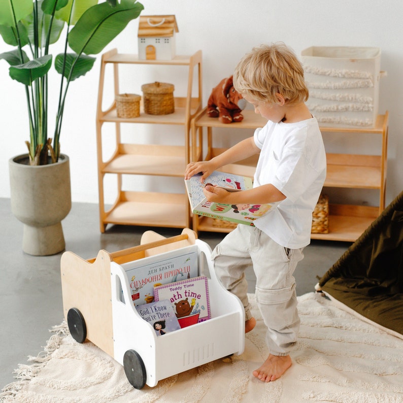 Puede incluir: Un cami&oacute;n de juguete blanco y de madera con ruedas, utilizado como porta libros. El cami&oacute;n est&aacute; lleno de libros infantiles coloridos con t&iacute;tulos como "Teddy Time" y "God, I Know You're There".