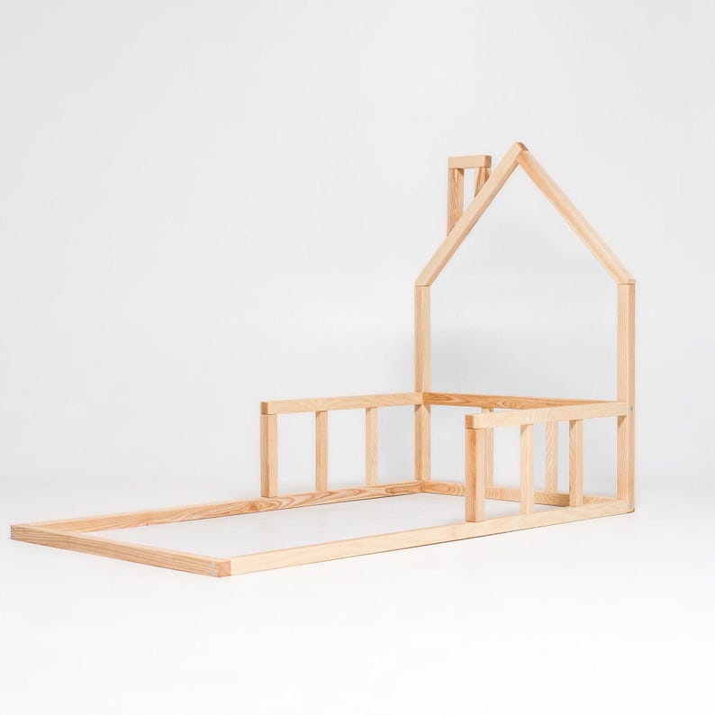 May include: A wooden bed frame shaped like a house with a chimney. The frame is made of unfinished wood and has a slatted headboard and footboard.