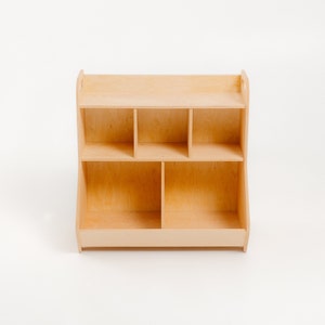 K&ouml;nnte beinhalten: Ein Holzregal mit sechs offenen F&auml;chern. Das Regal ist aus hellem Holz und hat ein schlichtes Design.