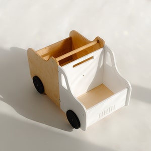 Puede incluir: Un cami&oacute;n de juguete de madera blanca y natural con ruedas negras. El cami&oacute;n tiene una caja extra&iacute;ble en la parte trasera y un estante en la parte delantera. El cami&oacute;n es un juguete para ni&ntilde;os.