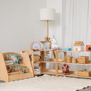 May include: A set of two wooden shelves with three shelves each. The shelves are filled with various items, including books, baskets, toys, and a unicorn plush. The shelves are in a light wood color and have a simple design.
