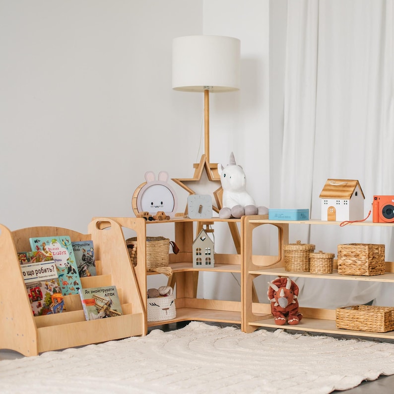 May include: A set of two wooden shelves with three shelves each. The shelves are filled with various items, including books, baskets, toys, and a unicorn plush. The shelves are in a light wood color and have a simple design.