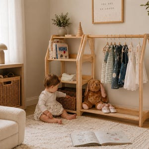 K&ouml;nnte beinhalten: Ein helles, h&ouml;lzernes Kinderkleiderst&auml;nder- und Regalm&ouml;belst&uuml;ck mit A-f&ouml;rmigem Design. Das M&ouml;belst&uuml;ck verf&uuml;gt &uuml;ber drei offene Regalb&ouml;den f&uuml;r B&uuml;cher und Aufbewahrungsk&ouml;rbe, eine Kleiderstange mit mehreren kleinen Kleidungsst&uuml;cken und eine Ablage.