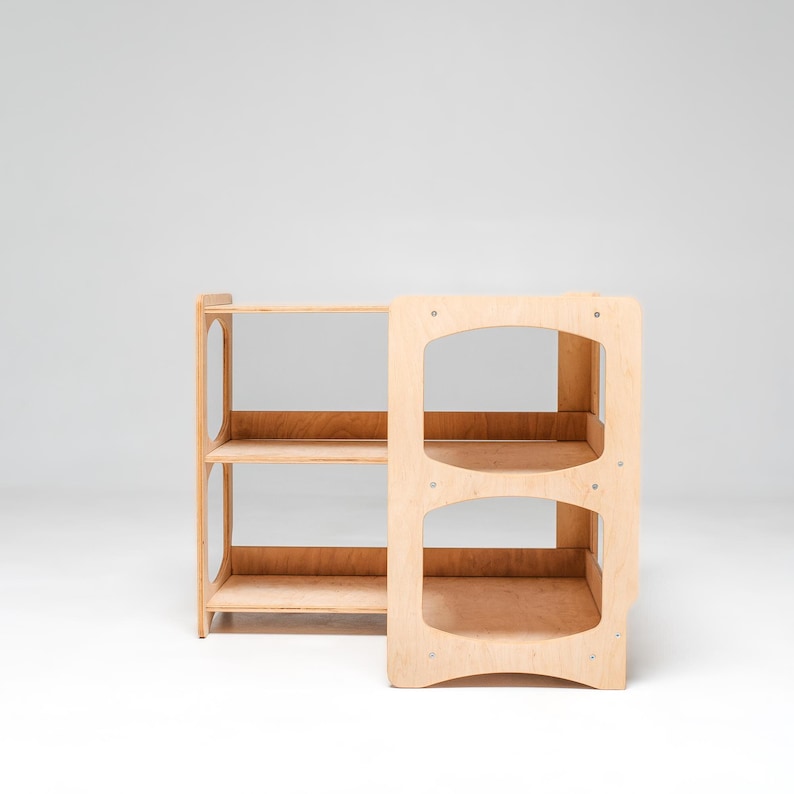 May include: A wooden shelf unit with two shelves on the left side and three shelves on the right side. The shelves are made of light wood and have a natural finish.