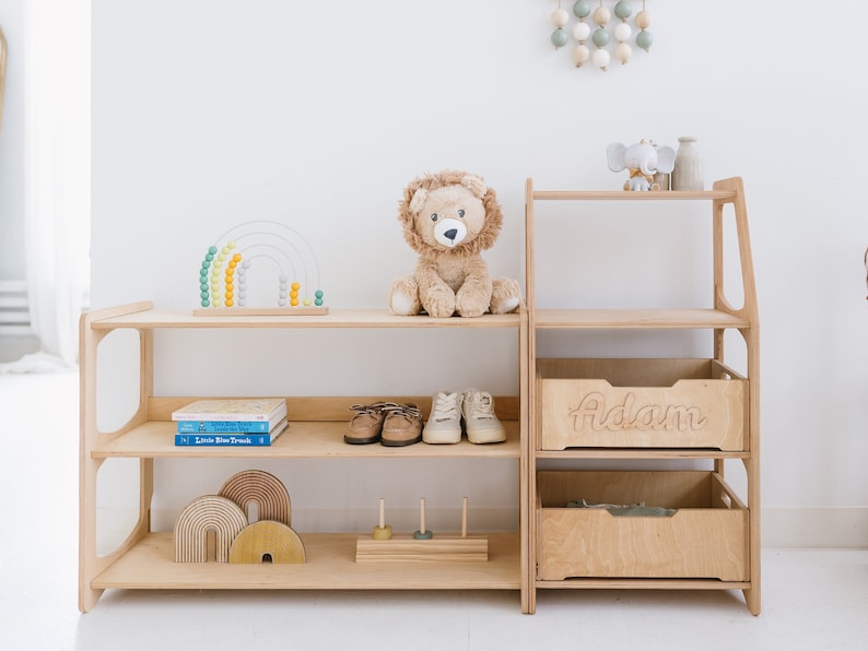 May include: A wooden shelf unit with two shelves and a drawer. The drawer is labeled "Adam". The shelf unit is filled with toys, including a stuffed lion, a rainbow abacus, and wooden blocks.