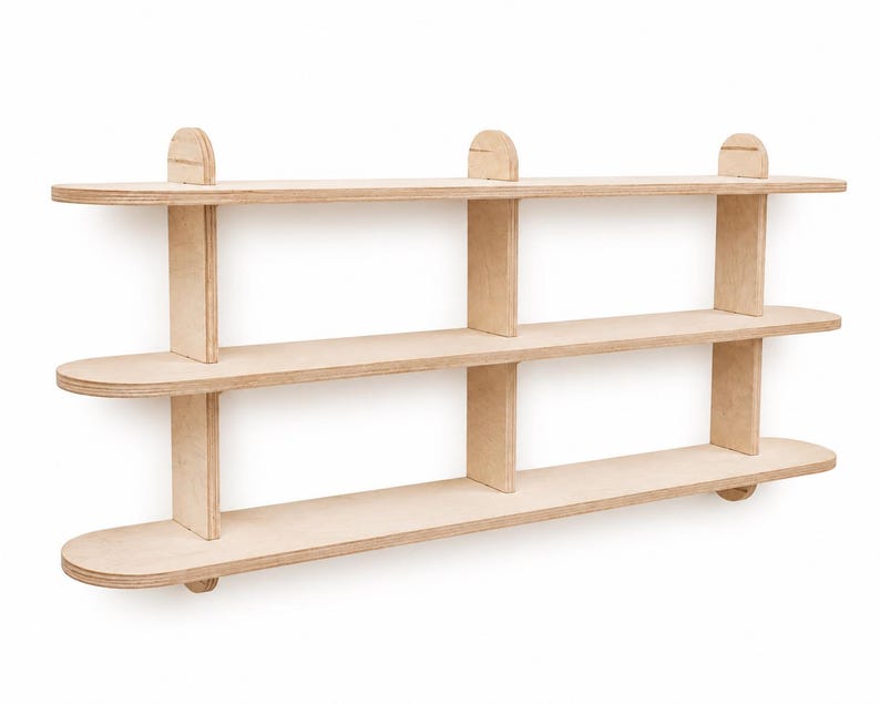 May include: A three-tiered wall-mounted shelf unit constructed from light-colored plywood. The unit features three horizontal shelves with rounded ends, supported by vertical dividers and small semi-circular accents along the top edge.