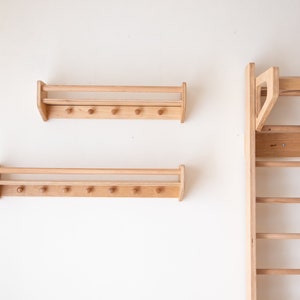 Pu&ograve; includere: Due mensole a muro in legno con una rotaia e ganci, e una sbarra per trazioni a muro in legno con pi&ugrave; pioli.
