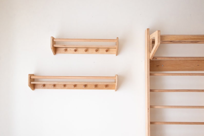 Pu&ograve; includere: Due mensole a muro in legno con una rotaia e ganci, e una sbarra per trazioni a muro in legno con pi&ugrave; pioli.