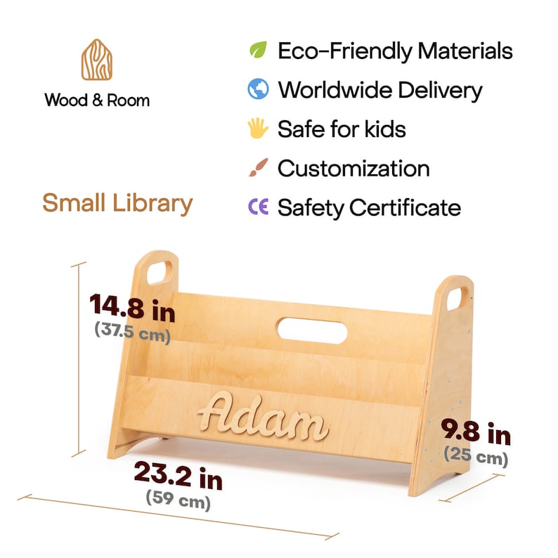 Puede incluir: Una estanter&iacute;a de libros de madera para ni&ntilde;os con un nombre personalizado, "Adam", en letra cursiva. La estanter&iacute;a mide 37,5 cm de alto, 59 cm de ancho y 25 cm de profundidad.