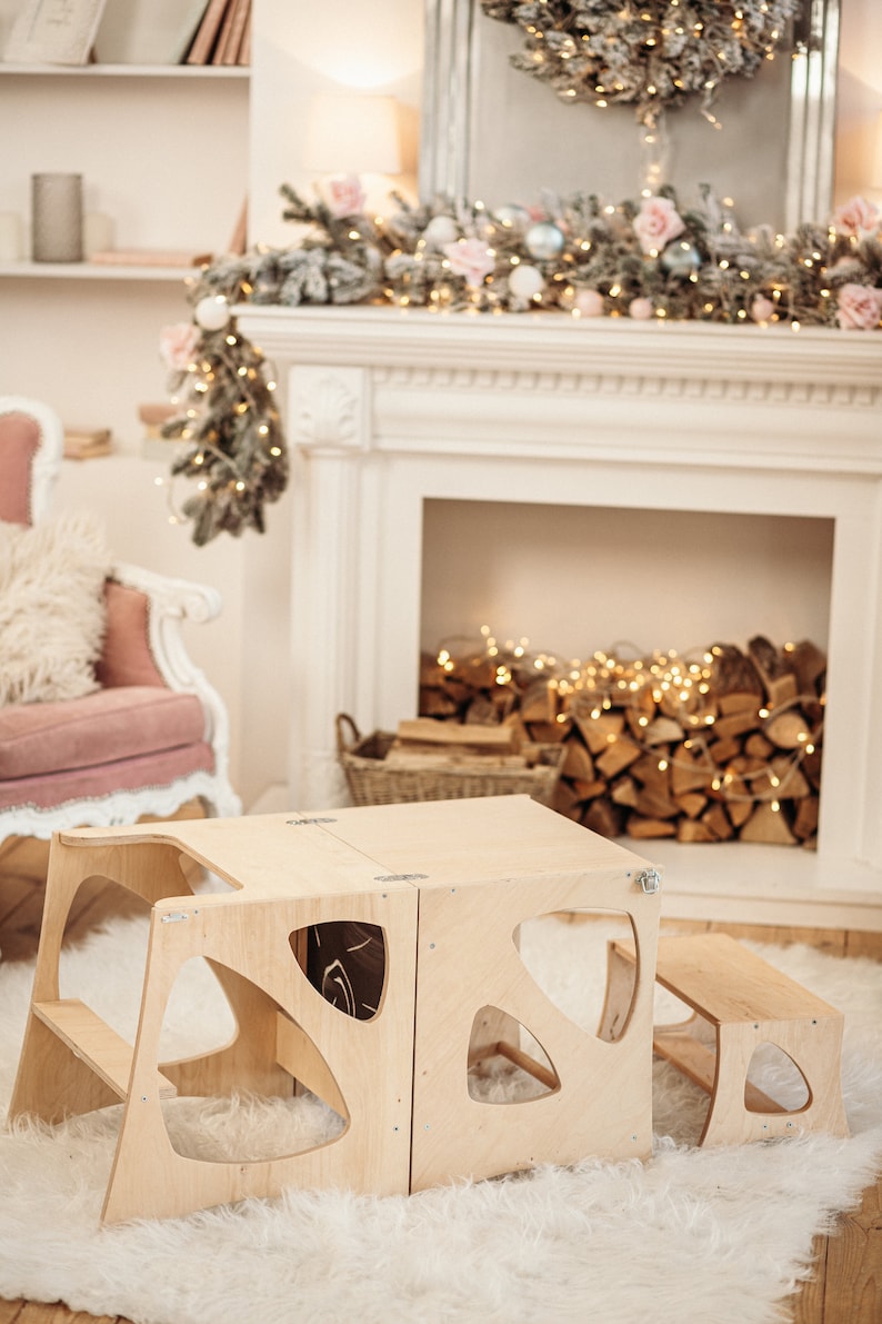 May include: A wooden children's table and chairs set with a unique cutout design. The table and chairs are made of natural wood and have a light brown finish. The set is perfect for a playroom or a child's bedroom.