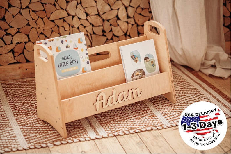 Puede incluir: Porta libros de madera con dos estantes y un nombre personalizado "Adam" en letra cursiva. El porta libros est&aacute; hecho de madera natural y se muestra en una alfombra marr&oacute;n y blanca.