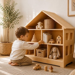 Toddler boy playing beside a wooden Montessori dollhouse bookshelf in a bright neutral playroom