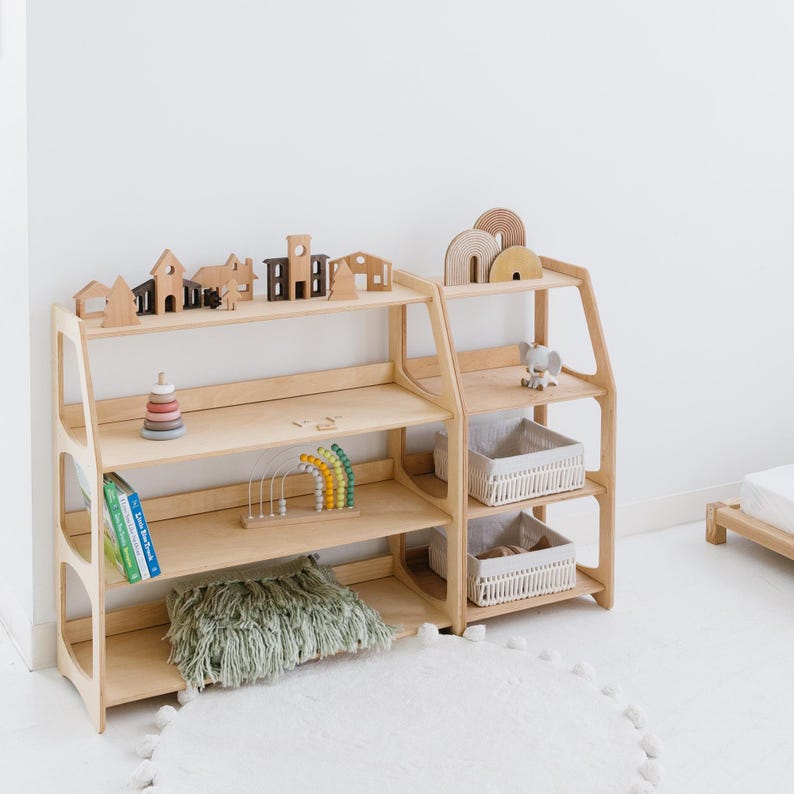 Pode incluir: Um conjunto de duas prateleiras de madeira com quatro prateleiras cada. As prateleiras s&atilde;o feitas de madeira natural e t&ecirc;m um acabamento marrom claro. As prateleiras est&atilde;o cheias de v&aacute;rios brinquedos, incluindo blocos de madeira, um brinquedo arco-&iacute;ris e uma pilha de an&eacute;is. H&aacute; um travesseiro verde felpudo na prateleira inferior.