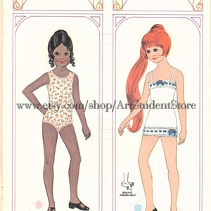 May include: A vintage paper doll set featuring two dolls, one with brown skin and black hair wearing a floral swimsuit, and the other with red hair wearing a white dress with blue trim. The dolls are standing on a white background with a pink and blue stand assembly.