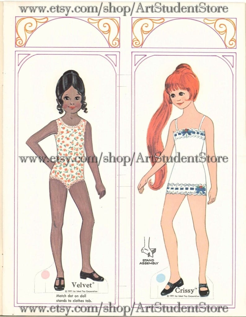 May include: A vintage paper doll set featuring two dolls, one with brown skin and black hair wearing a floral swimsuit, and the other with red hair wearing a white dress with blue trim. The dolls are standing on a white background with a pink and blue stand assembly.