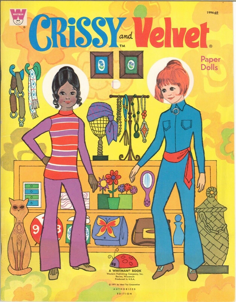 May include: A vintage paper doll book featuring Crissy and Velvet. The cover shows the two dolls in colorful outfits, standing in front of a store display with accessories. The book is titled "Crissy and Velvet Paper Dolls" and includes the text "A Whitman Book".