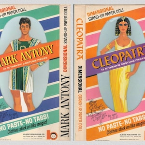 May include: Two vintage paper doll sets, one of Mark Antony and the other of Cleopatra. Both boxes feature colorful stripes and the dolls are depicted in their iconic attire. The text on the boxes reads "Dimensional Stand-Up Paper Doll" and includes the names of the historical figures. The boxes also state "13 Authentic Costume Pieces" and "No Paste-No Tabs! Clothes stick on like magic!"