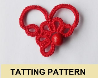 May include: Red tatting pattern with a red bead in the center. The pattern is in the shape of a heart.