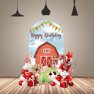 Puede incluir: Un granero rojo con una puerta y ventanas blancas, rodeado de hierba verde y animales de granja. El granero es parte de un telón de fondo para una fiesta de cumpleaños, con globos rojos y blancos, bastones de caramelo y un letrero que dice "Feliz cumpleaños".