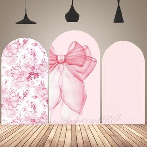 Könnte beinhalten: Ein dreiteiliger Hintergrund mit Bogenmuster. Die linke Tafel zeigt ein Blumenmuster in Rosa und Weiß. Die mittlere Tafel zeigt eine große rosa Schleife. Die rechte Tafel ist einfarbig hellrosa. Der Hintergrund steht auf einem Holzboden.