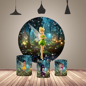 May include: A large circular backdrop and three cylindrical pedestals featuring a forest scene with Tinker Bell and other fairies. The imagery includes glowing lights, dark trees, and sparkling effects. The central fairy wears a green dress.