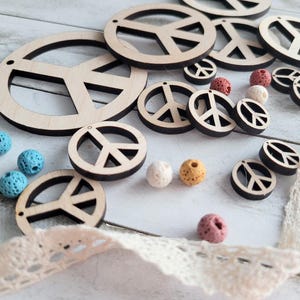 May include: A collection of wooden peace sign ornaments in various sizes, with some smaller peace signs and colorful beads scattered around them.