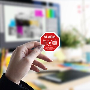 Può includere: Un cartello ottagonale rosso con la parola "ALARM" in testo bianco. Il cartello ha un cerchio bianco con un punto nero al centro e linee ondulate bianche su entrambi i lati del cerchio. Il cartello ha anche il testo "Dieses Objekt wird elektronisch gesichert" in testo bianco.