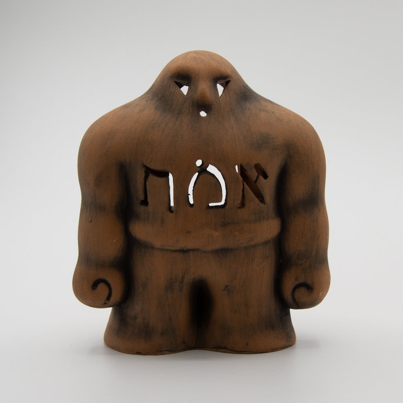May include: A brown ceramic figurine of a muscular figure with the word "אומץ" (Hebrew for "courage") carved into its chest.