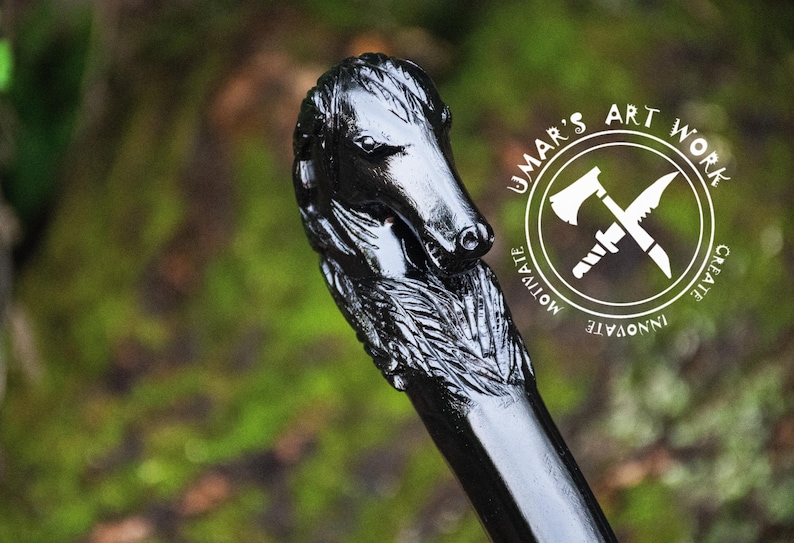 May include: Black wooden walking stick with a carved dog head handle. The handle is detailed with fur and the dog's head is looking to the side. The stick is polished and has a smooth finish. The image also includes a logo with the text "UMAR'S ART WORK" and the words "CREATE, INNOVATE, MOTIVATE".