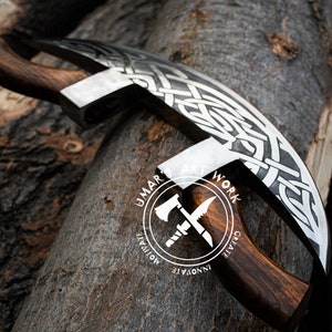 May include: A curved metal blade with an intricate silver-toned Celtic knotwork pattern and a dark brown wooden handle. The blade features a circular logo with the text UMAR'S ART WORK, CREATE, INNOVATE, MOTIVATE, and an axe and knife icon.