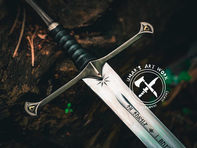 May include: A detailed image of a silver sword with a black leather-wrapped handle. The blade has etched inscriptions and a star design. The hilt features gold accents. The sword is set against a dark, textured background, with the text "UMAR'S ART WORK" in a circular logo.