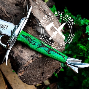 May include: A silver sword with a green and black wooden handle. The handle has a decorative design and the text "UMAR'S ART WORK CREATE INNOVATE MOTIVATE" is on the handle.