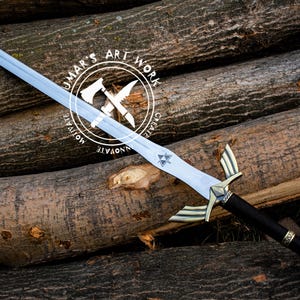 May include: A silver-bladed sword with a black handle and gold accents, resting on a pile of logs. The sword features a distinctive hilt design and a Triforce symbol on the blade. The text "UMAR'S ART WORK" is in a circular logo.