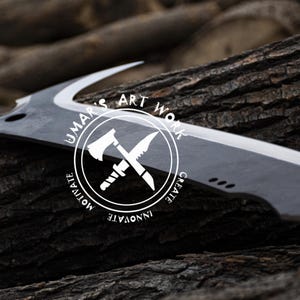 K&ouml;nnte beinhalten: Ein gro&szlig;es Messer mit gebogener Klinge, dunklem Metallfinish und Holzgriff. Die Klinge hat eine scharfe Kante und eine markante Form. Das Messer liegt auf einem Holzbett. Der Text "UMAR'S ART WORK" befindet sich in einem wei&szlig;en Kreis.